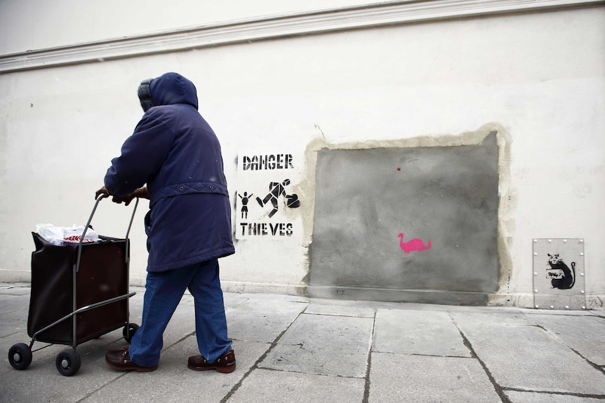 A woman walks past a section of a wall where celebrated street artist Banksy's Slave Labour graffiti artwork was removed.