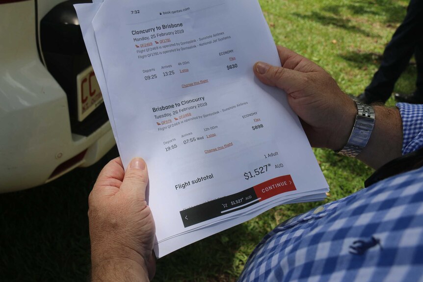 A man holds Qantas flight information showing the return cost from Brisbane to Cloncurry is $1,527.