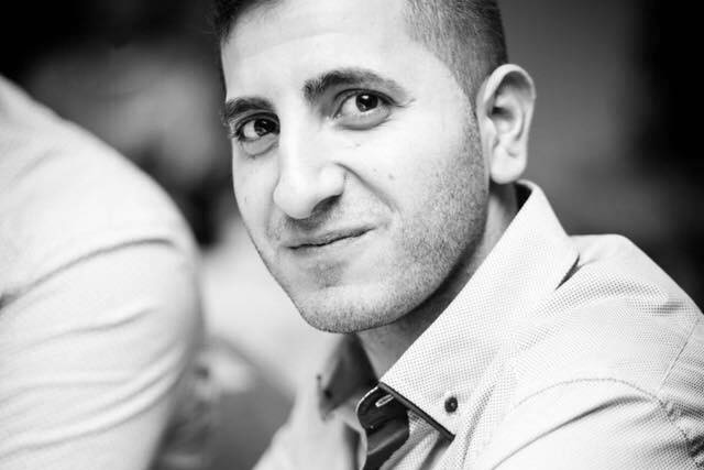 A black and white photo of a man smiling into the camera. 