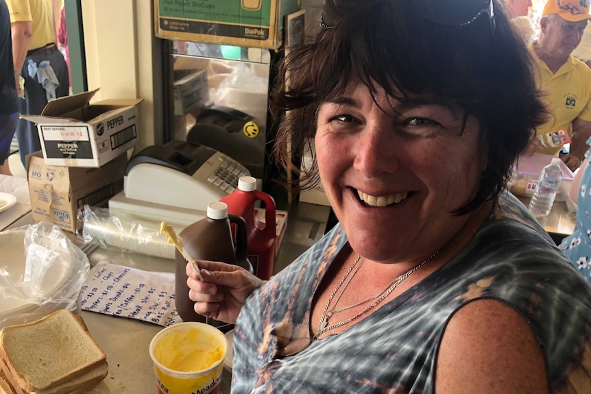 A woman smiling while buttering bread