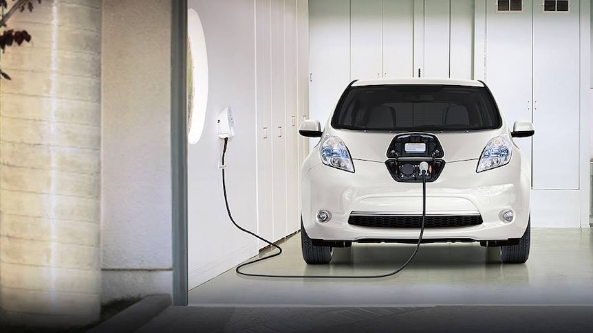 a small electric car plugged in to an electric charger inside a garage