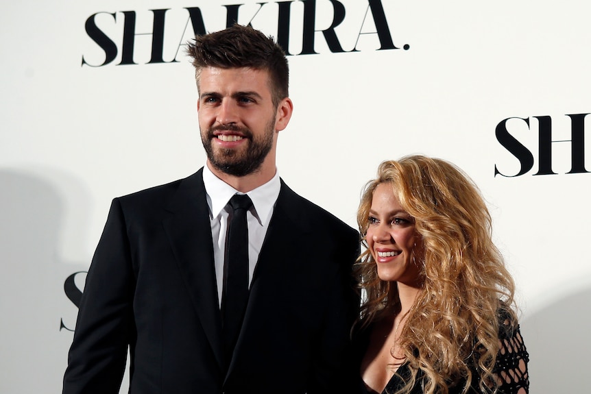 Shakira stands beside Gerard Pique during a photocall presenting her new album 'Shakira'. They're both wearing formal attire.