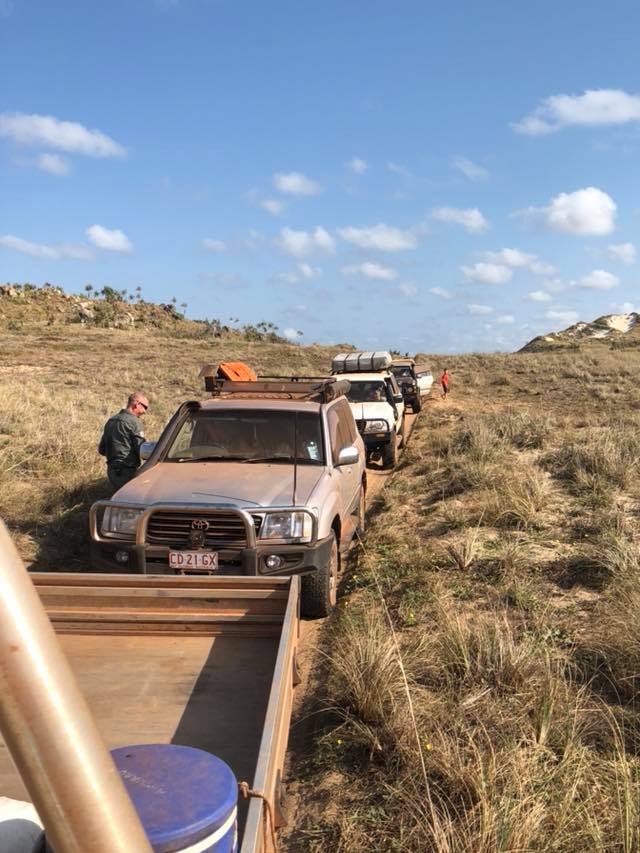 A portrait photo of a group of four-wheel drives travelling along a remote dirt track.