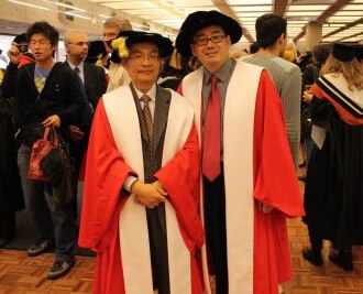 Two Chinese men in red academic robes smiling at the camera.