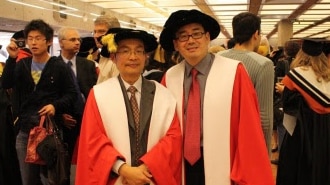 Two Chinese men in red academic robes smiling at the camera.