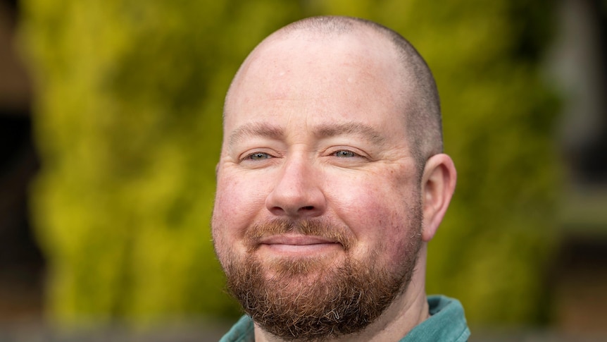 head shot of smiling man with beard wearing a green shirt