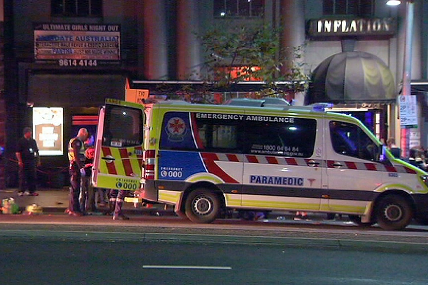 An ambulance Victoria parked outside of at Inflation nightclub, with its back doors open and police on scene.