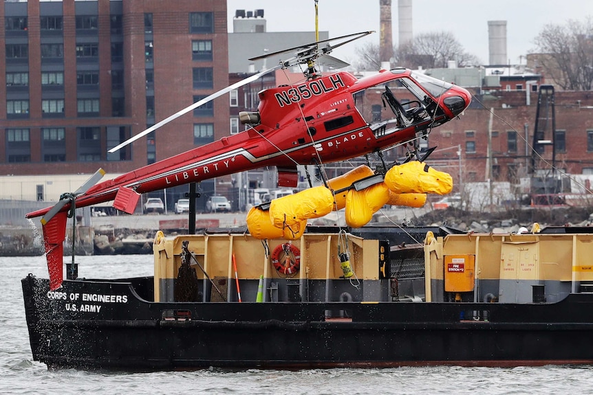 The helicopter is hoisted by crane from the East River.