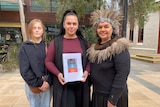 A Kaurna woman holds a dictionary, flanked by family members.