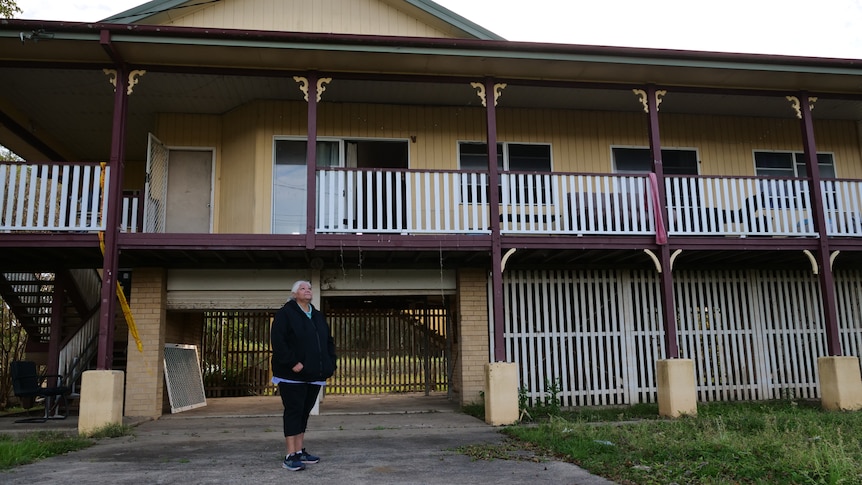 A woman standing in front of a large 2 story house