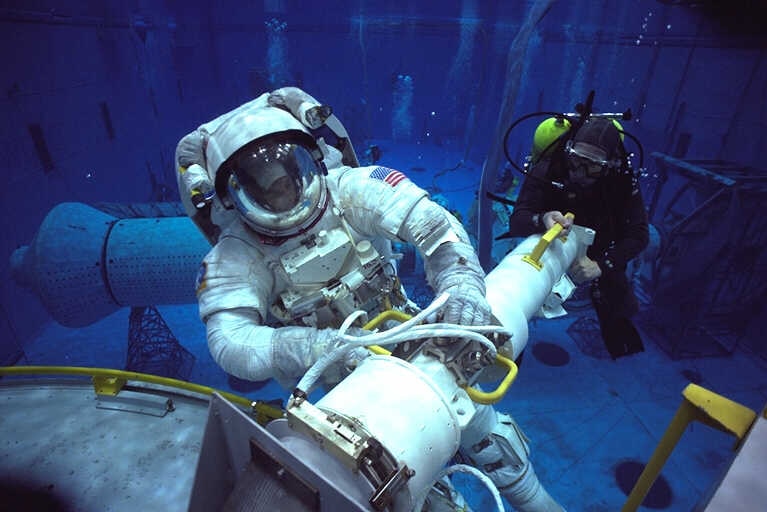 An astronaut in full space suit training in a pool