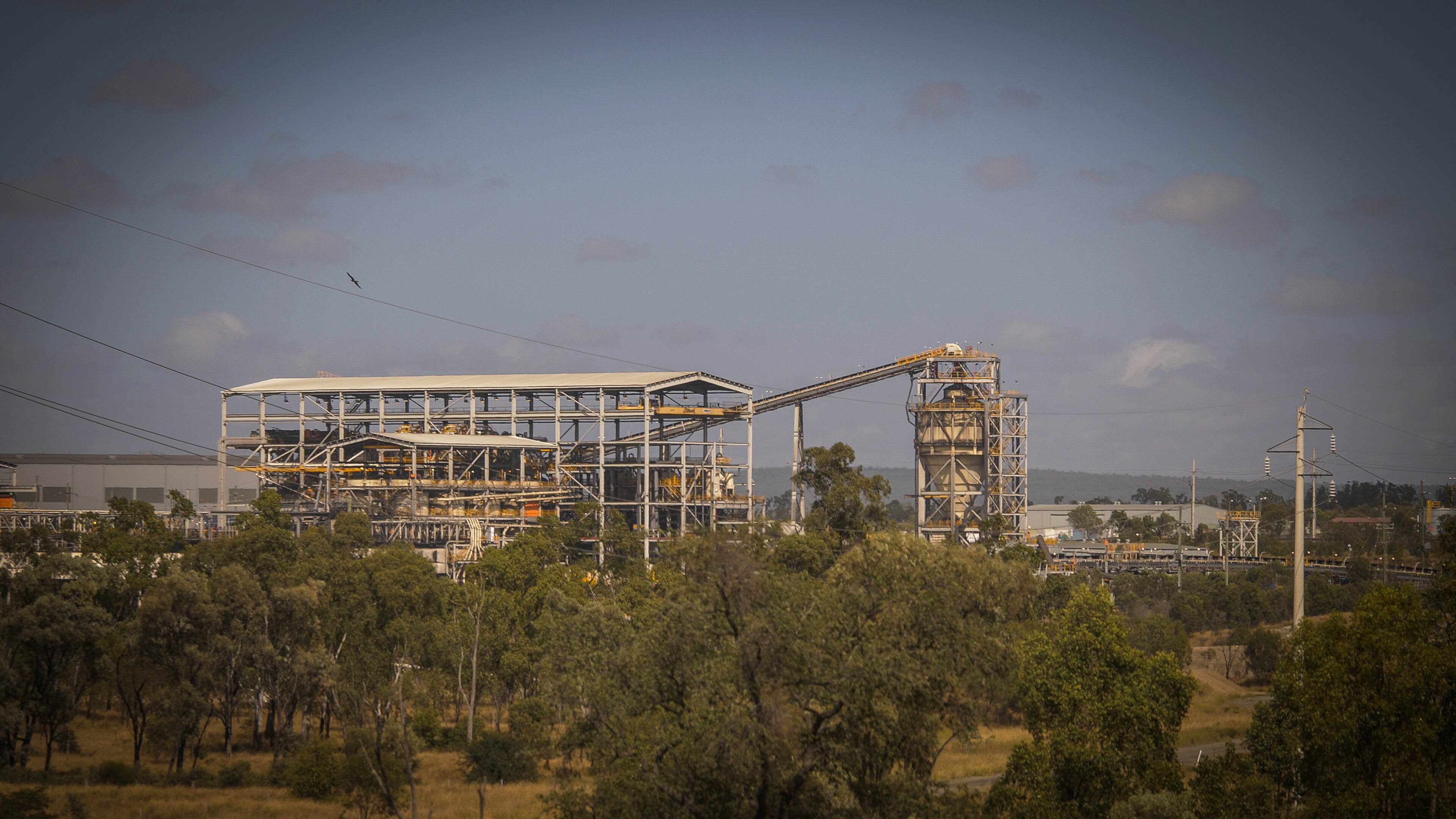 Coal mining infrastructure in the distance, surrounded by trees in the foreground.