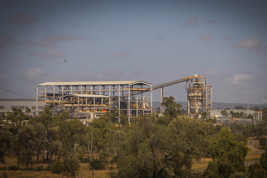 Coal mining infrastructure in the distance, surrounded by trees in the foreground.