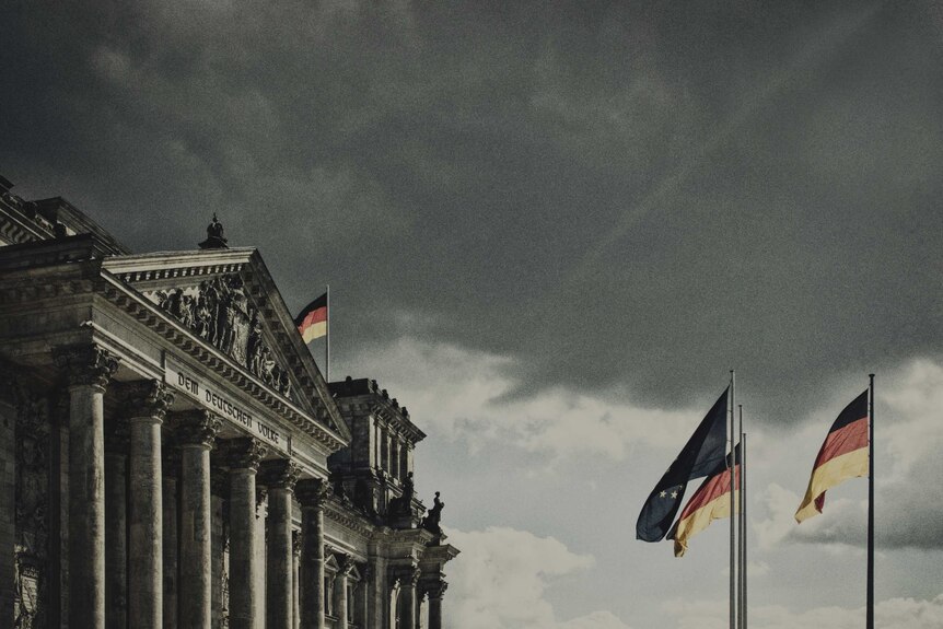 Landscape photo of the Reichstag building with the German flag out the front.