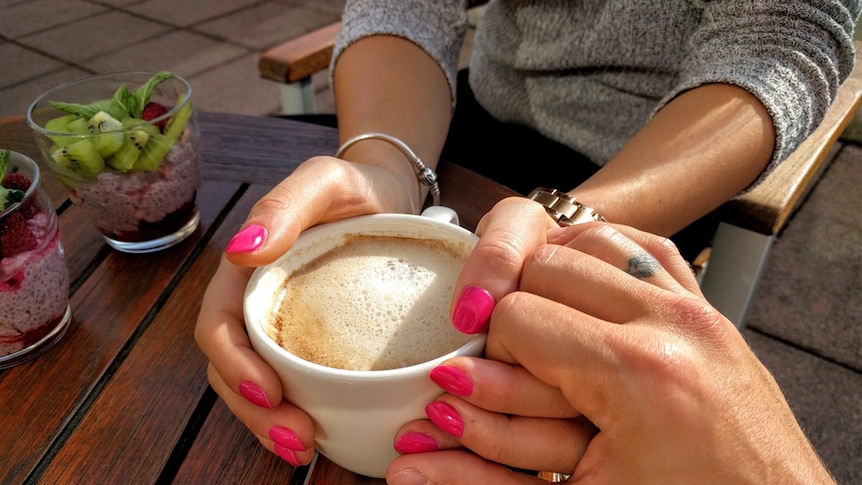 A couple holds hands across a table.