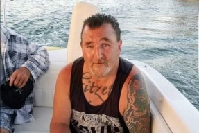 a man dressed in a black singlet sitting in a boat.
