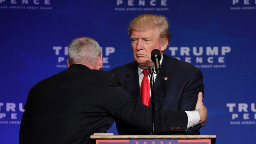 A member of the secret service pulls trump from the stage