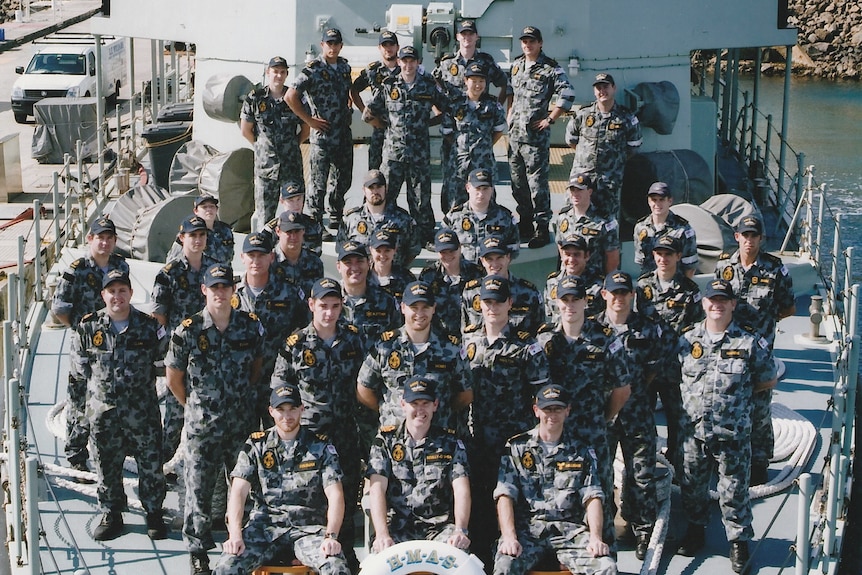 Group of men in naval uniforms on deck of a ship.