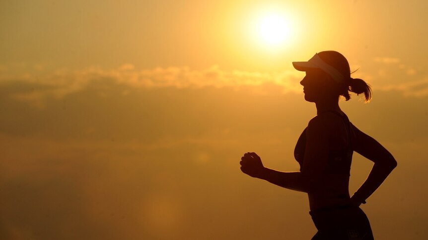 Silhouette of woman running with sunshine in the background