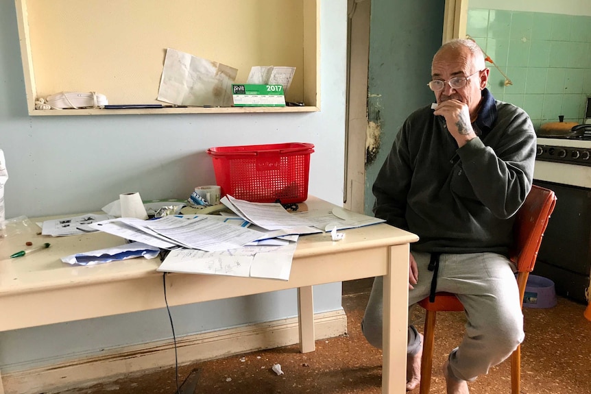 Arthur Johnson looks concerned as he rolls a cigarette at his kitchen table