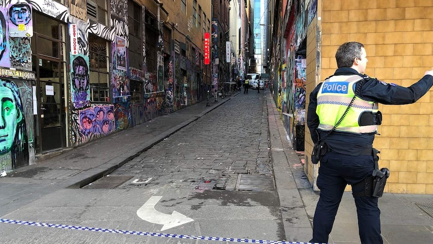 A policeman stands near police tape blocking off the graffiti-covered Hosier Lane in Melbourne.