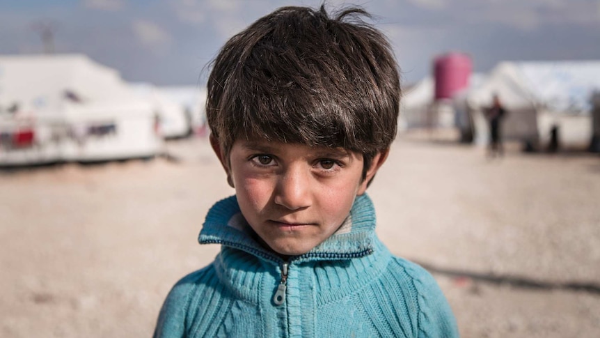 Syrian child Ibrahim next to his family's tent.