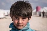 Syrian child Ibrahim next to his family's tent.