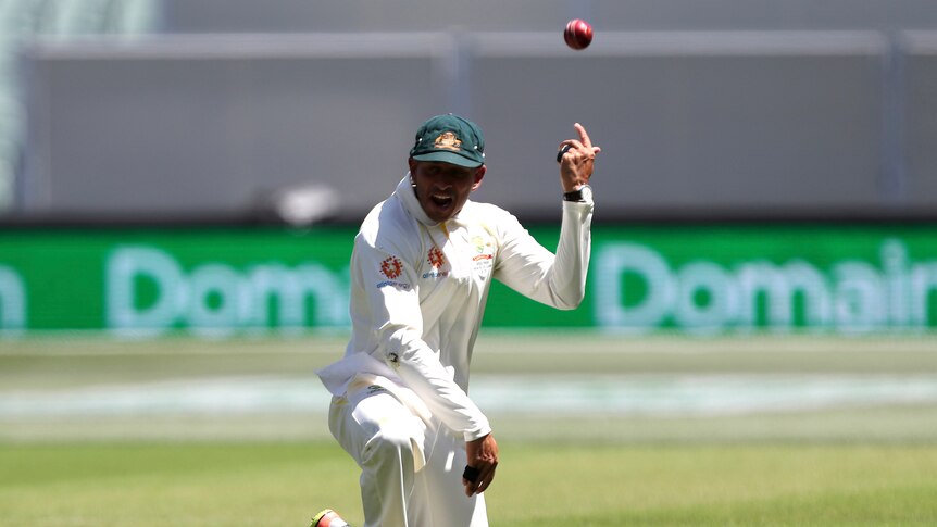 Uzman Khawaja throws the ball over his shoulder while down on one knee