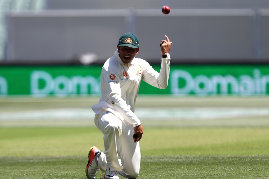 Uzman Khawaja throws the ball over his shoulder while down on one knee