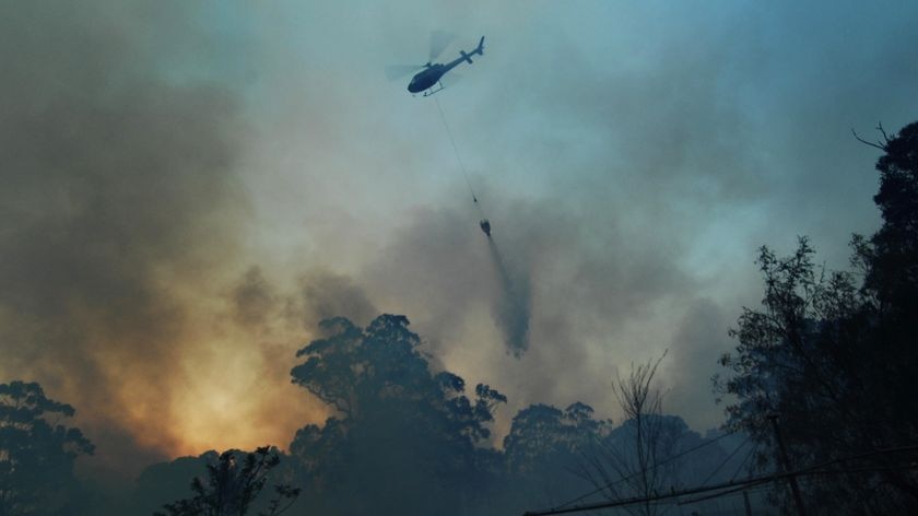A fire bombing helicopter dumps water on a blaze