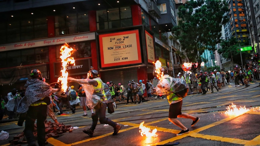 Members of the media run down a Hong Kong street after being hit by flames.