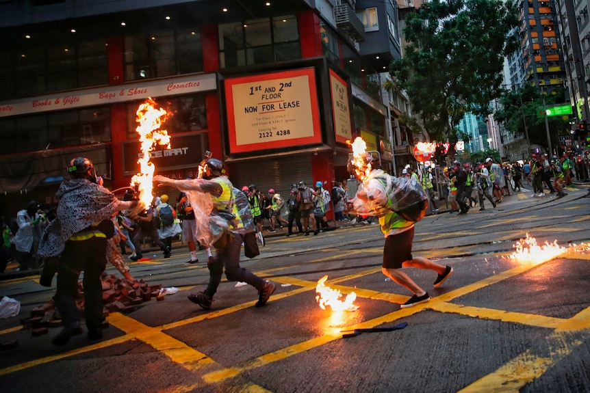 Members of the media run down a Hong Kong street after being hit by flames.