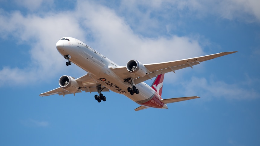 A photo of a Qantas plane flying in the sky. 