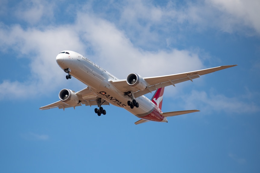 A photo of a Qantas plane flying in the sky. 