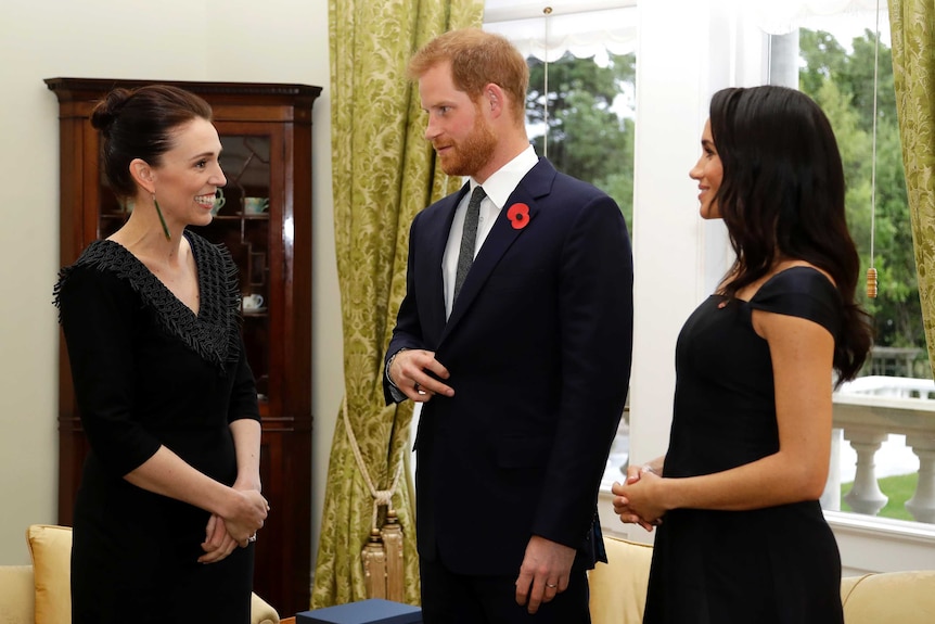 Three people in formal clothes standing together.