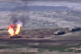 A grainty photograph shows a blurry tank on fire with two other military vehicles nearby.