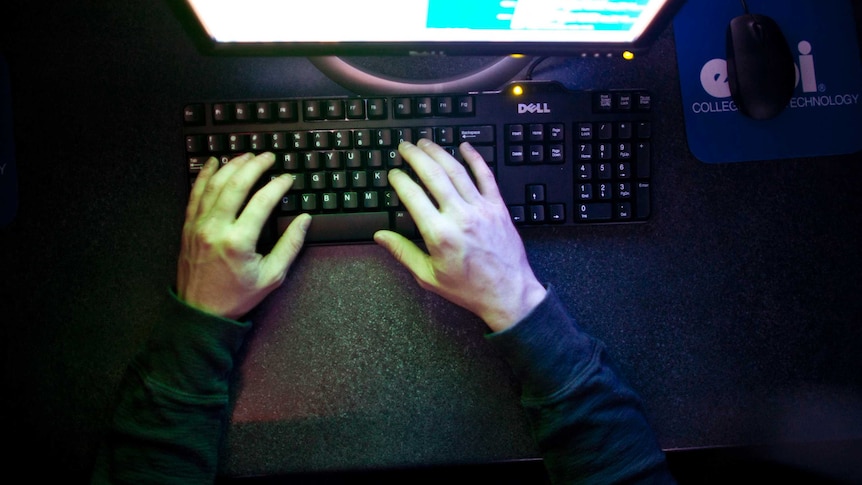 A man types on a computer keyboard.