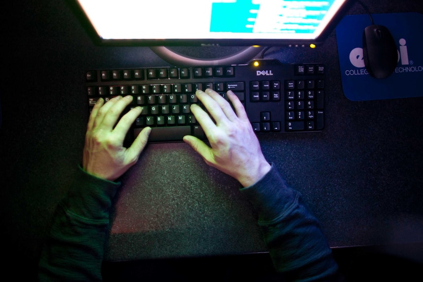 Hands on a keyboard in front of a computer screen.