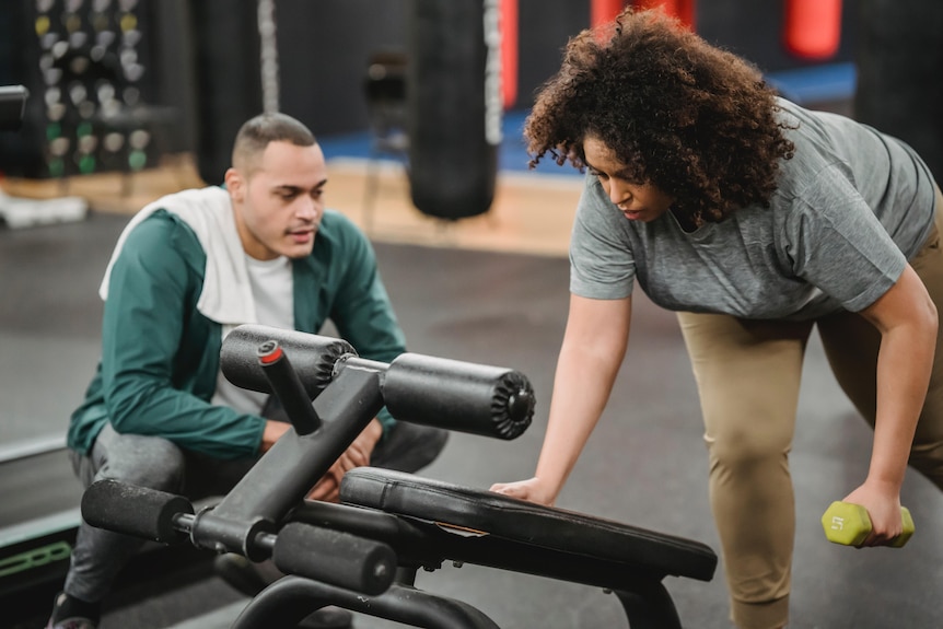 A woman trains with a dumbbell.