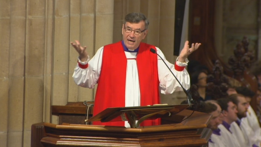 Glenn Davies preaches from a pulpit.