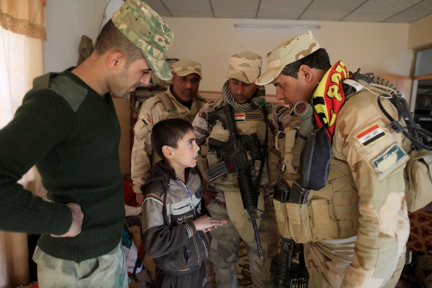 Iraqi soldiers talk to a boy