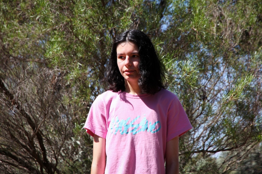 A teenage girl in a pink shirt with dark hair.