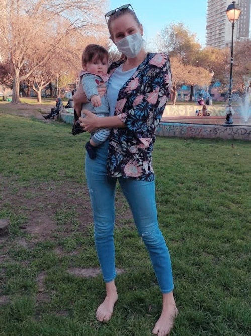 A woman holding a baby in a park.