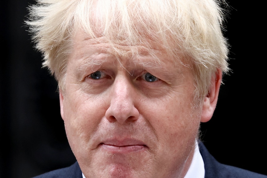 Un gros plan de Boris Johnson avec les larmes aux yeux et le vent soufflant dans ses cheveux.
