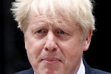 A close up of Boris Johnson with tears in his eyes and the wind blowing his hair.