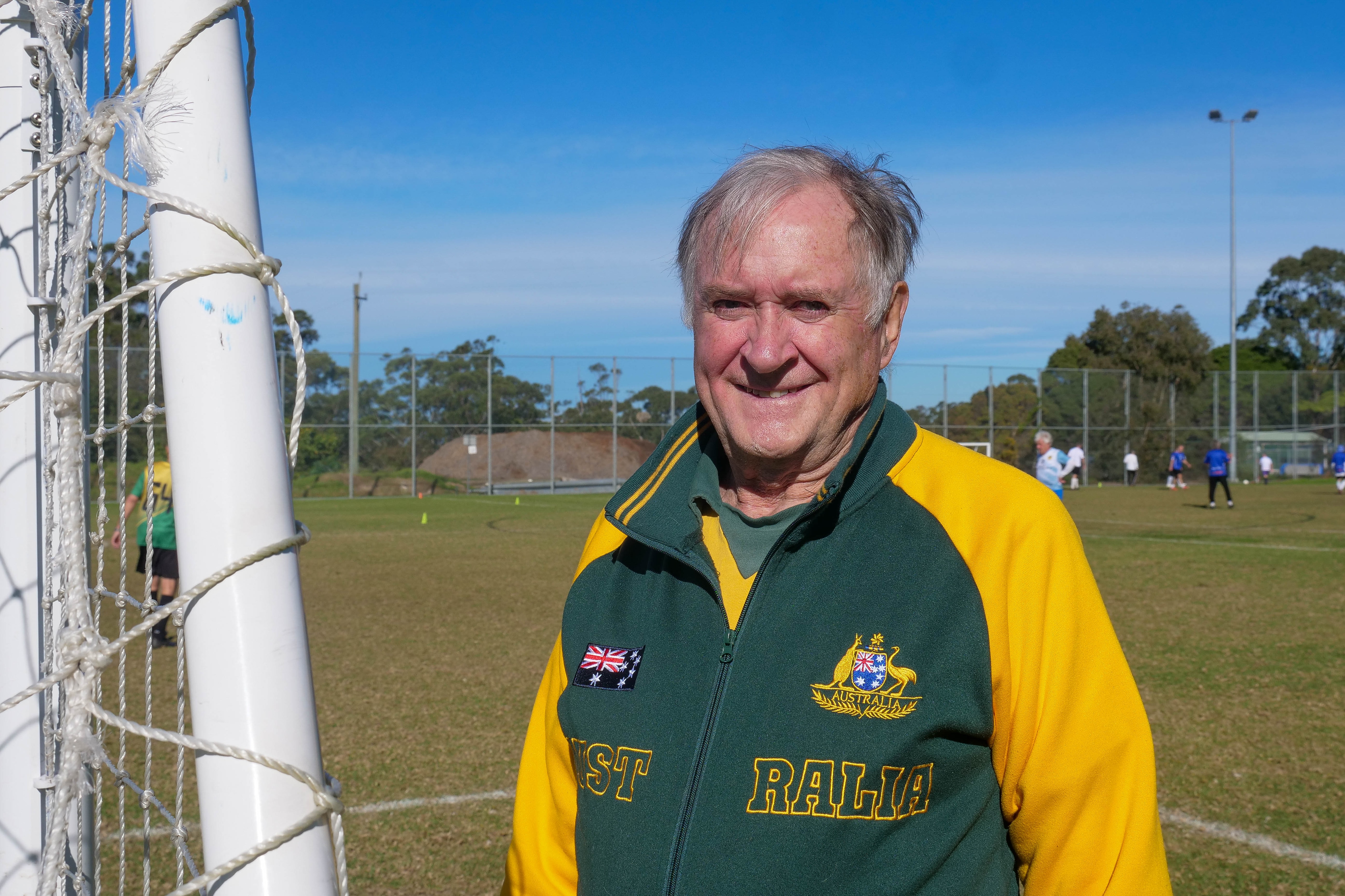 an older man wearing a green and gold australian-branded jumper