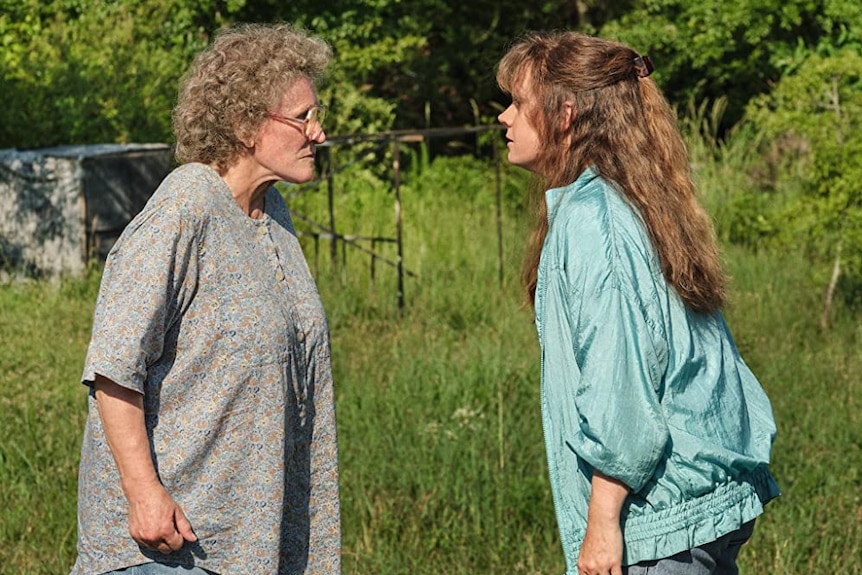 Actresses Amy Adams and Glenn Close stand in front of each other there is tall grass in the background