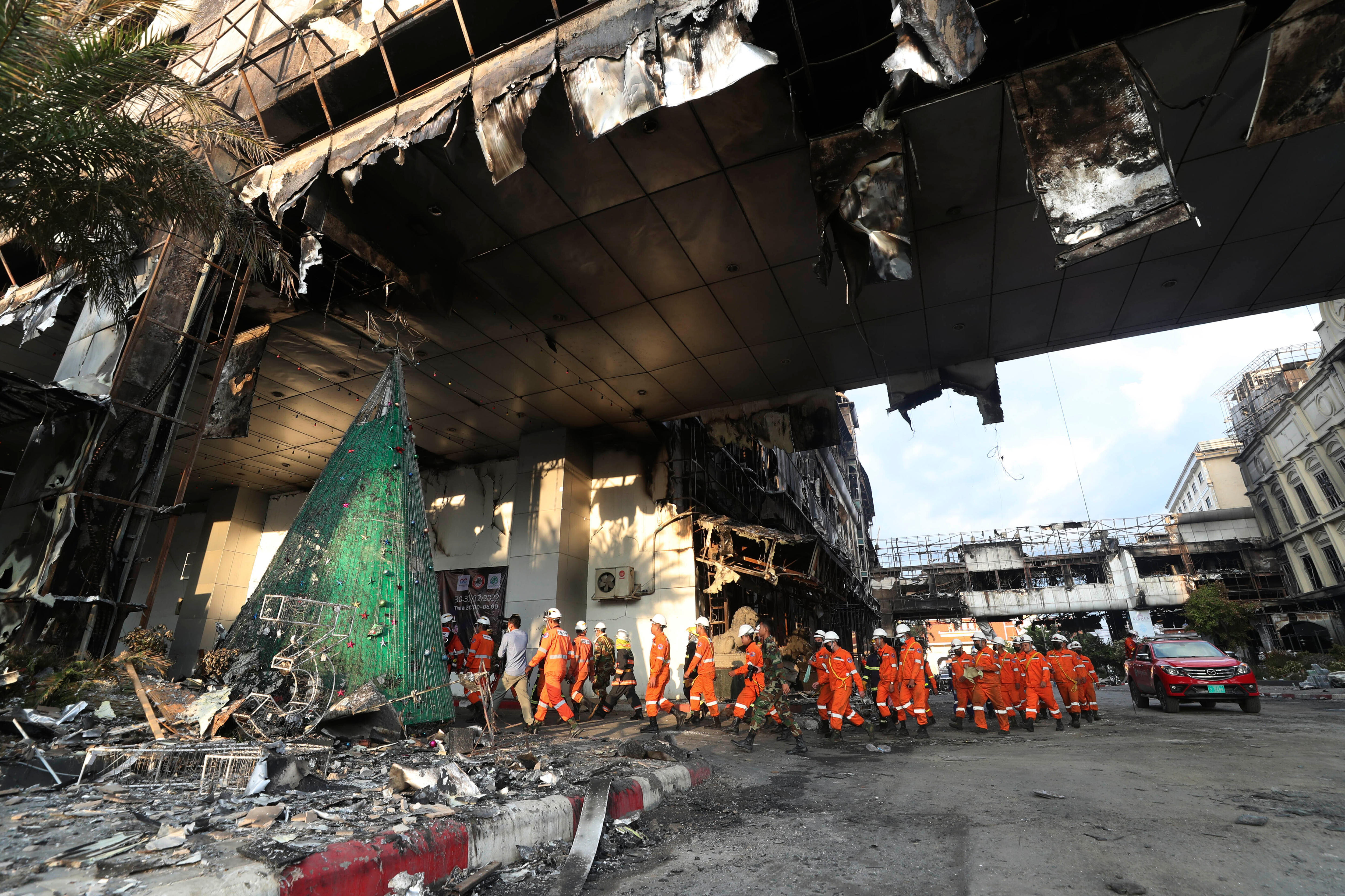Rescue experts in orange kit walk through a ruined building.