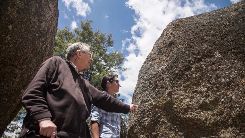 A man and woman looking at a giant boulder