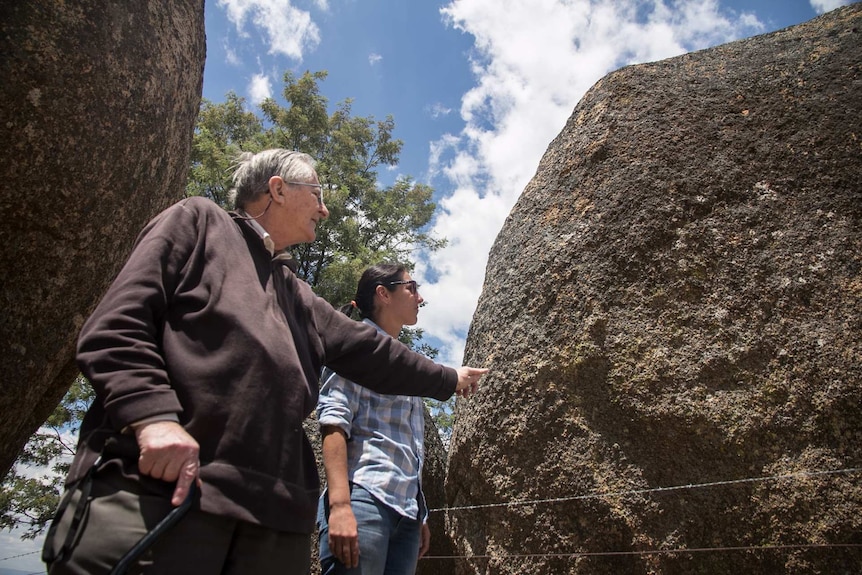 A man and woman looking at a giant boulder